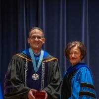 Provost Mili and man take picture on stage